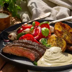 Perfekt stekt flankstek med klyftpotatis, tomatsallad och en krämig sås. En härlig måltid att njuta av utomhus.
