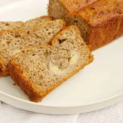 En saftig banankaka i långpanna, skuren i skivor och serverad på en vit tallrik. Perfekt för fikat!