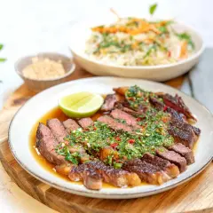 En saftig asiatisk biffsallad med skivad biff, lime och en örtig dressing. Serveras med en skål ris och sesamfrön.