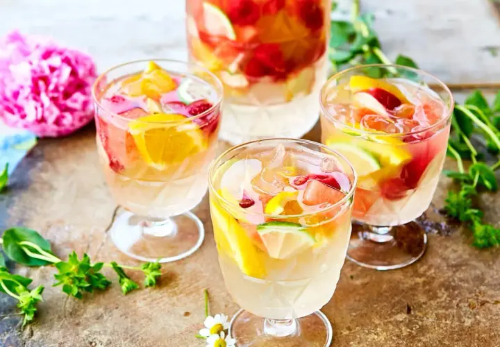 Tre glas med uppfriskande sangria vit fyllda med frukt och is. En perfekt sommardrink!