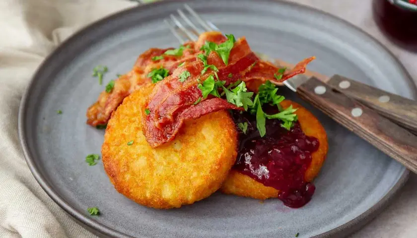 Gylla potatisbullar airfryer med knaprigt bacon, lingonsylt och persilja på en grå tallrik. En klassisk svensk rätt.