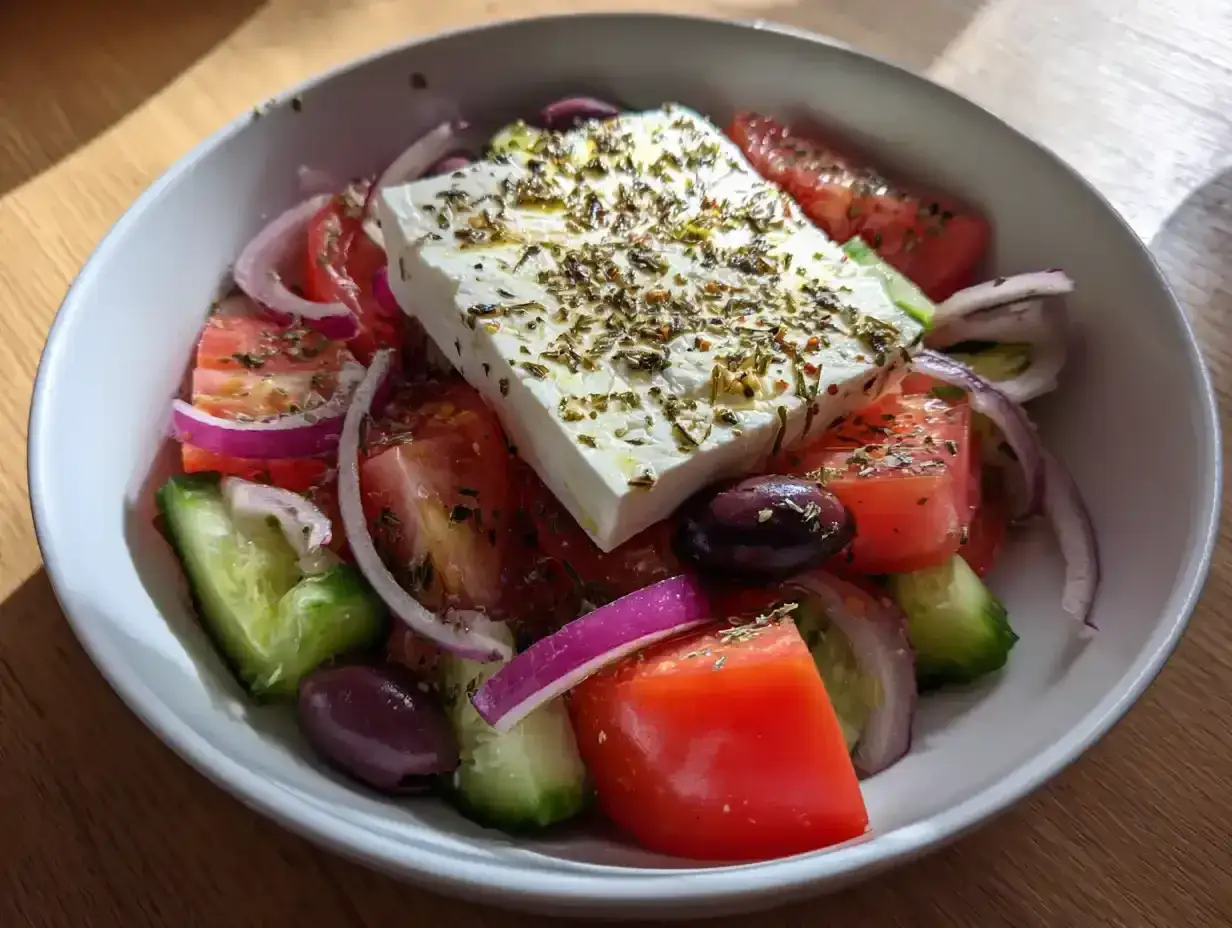 En fräsch grekisk sallad med fetaost, tomater, gurka, rödlök och oliver, toppad med örter.