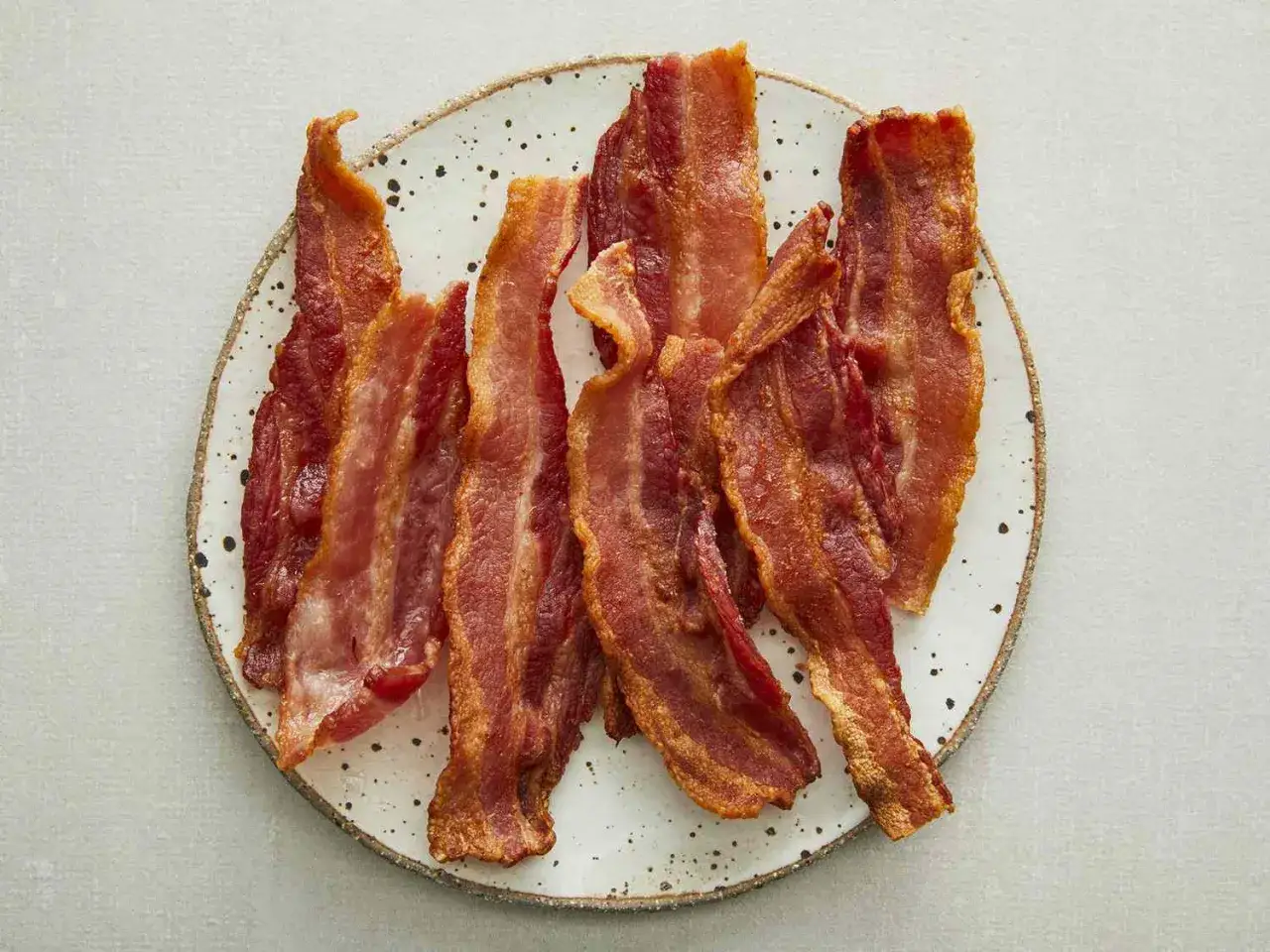 Krispigt stekt bacon i airfryer, serverat p&aring; en tallrik. Perfekt f&ouml;r en lyxig frukost.