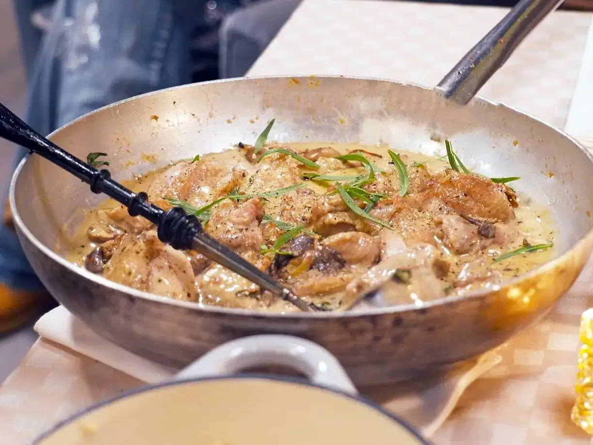 En panna med krämig coq au vin blanc, kycklingbitar, svamp och örter.