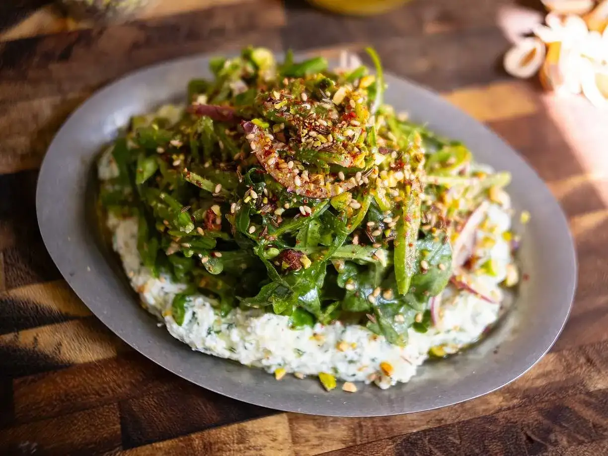 En krämig bas med en fräsch sallad till pajen, toppad med nötter och frön.