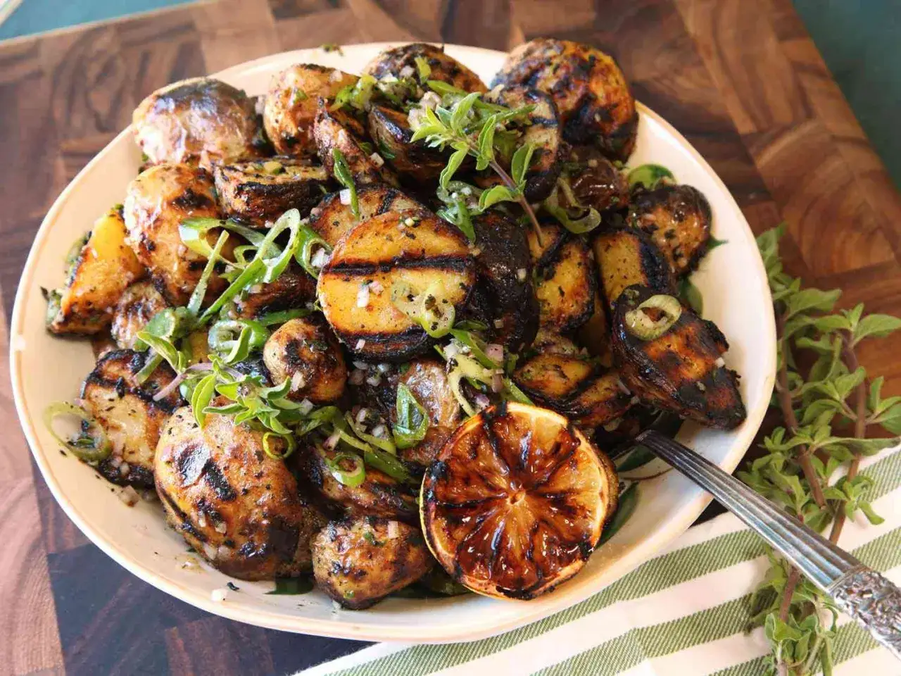 En härlig rostad potatissallad med grillade potatisar, färska örter och en karamelliserad citronklyfta. Perfekt till sommarens grillkvällar!