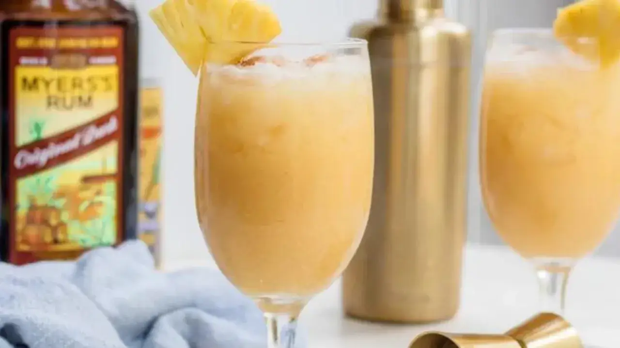 En härlig gul drink med ananas, Myers's Rum och en shaker i bakgrunden. Perfekt för en solig dag!