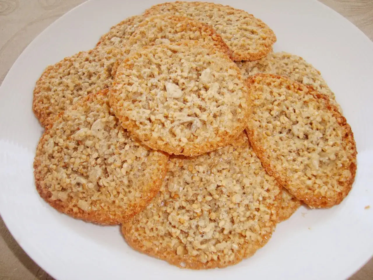 En h&ouml;g med krispiga, gyllene glutenfria havreflarn p&aring; en vit tallrik. Perfekta f&ouml;r fikat!