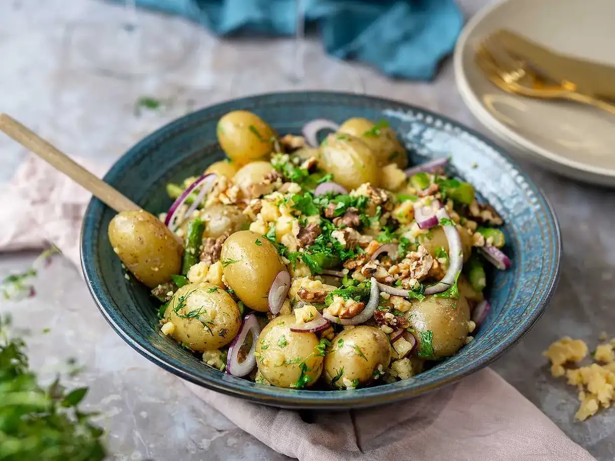 En härlig potatissallad med sparris, rödlök och valnötter, toppad med färska örter. Perfekt som tillbehör!