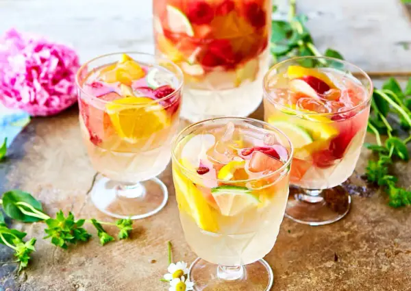 Tre glas med uppfriskande sangria vit fyllda med frukt och is. En perfekt sommardrink!